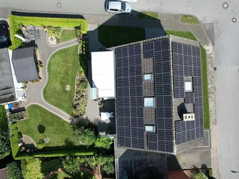 Aerial view of a residential house with a full solar panel rooftop installation